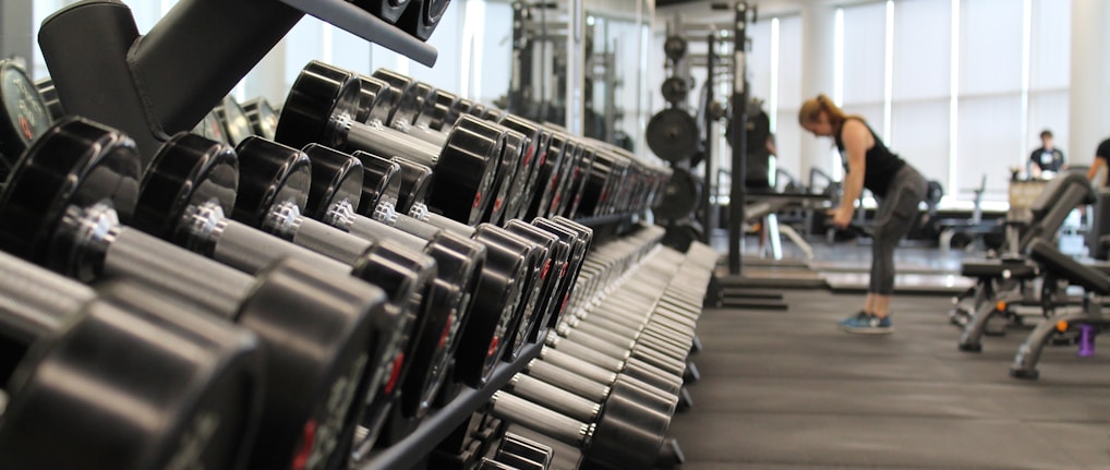 woman standing surrounded by exercise equipment gym maintained by professional cleaners