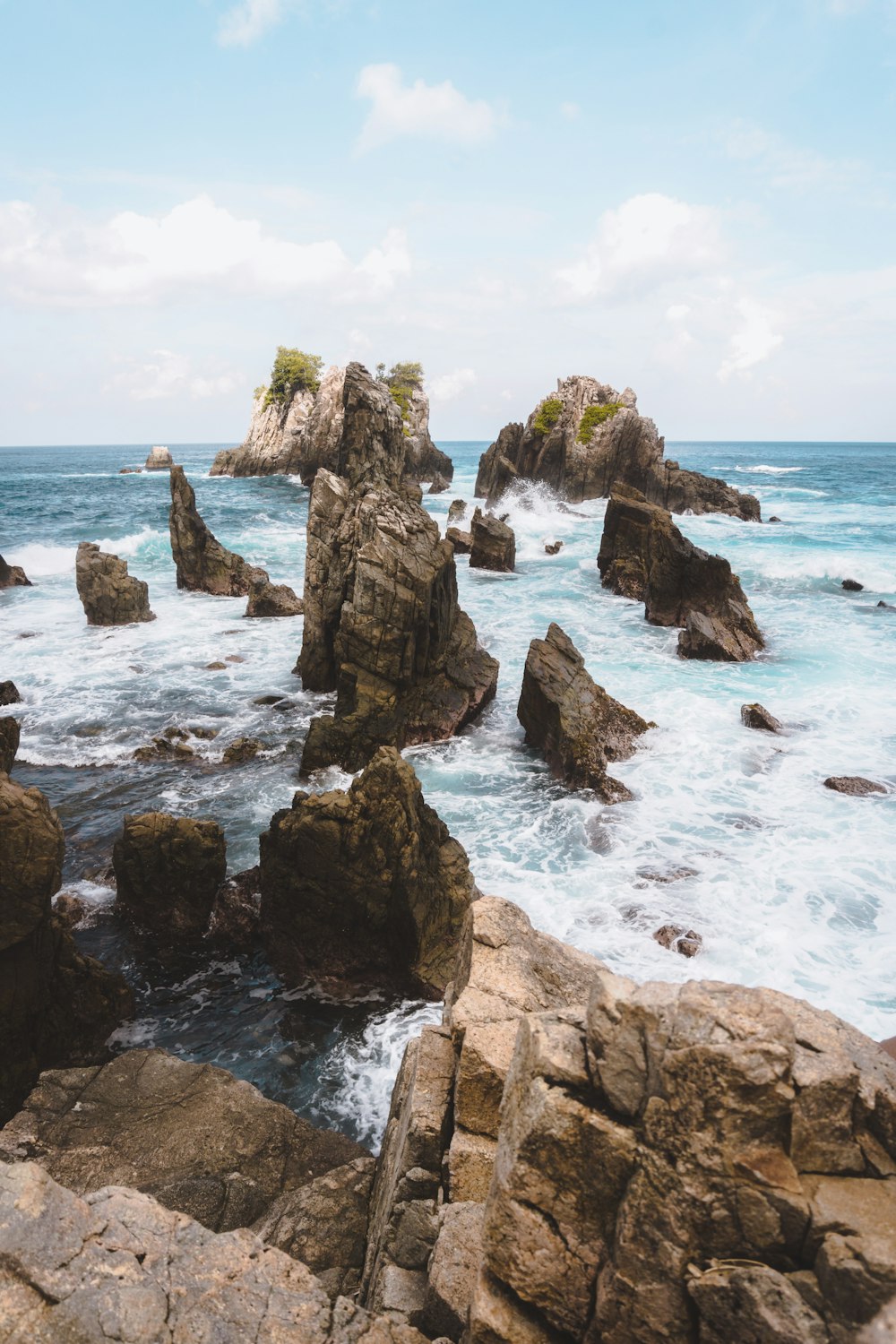 time-lapse photography of rock formations by the sea under cloudy sky