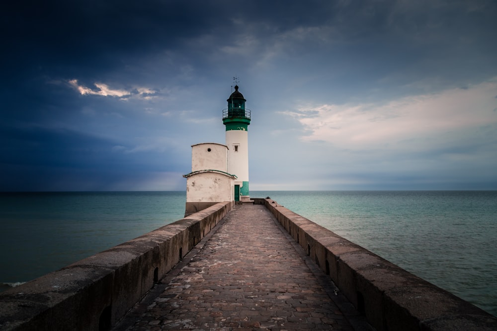 white and green lighthouse beside sea