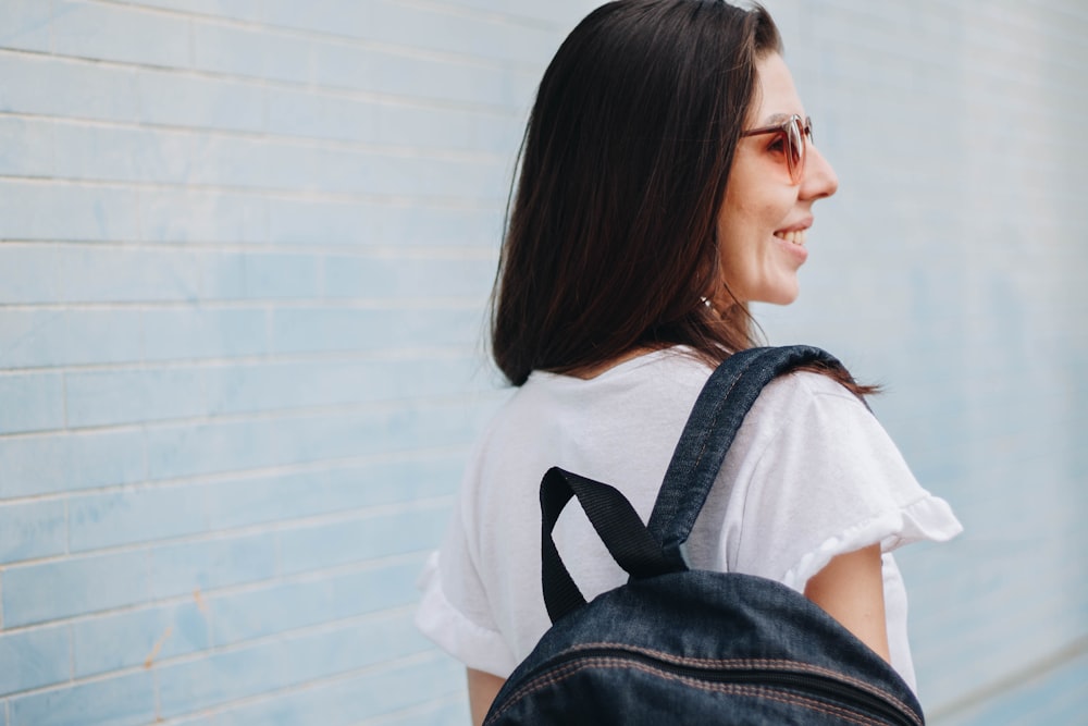 woman smiling while carrying blue denim backpack