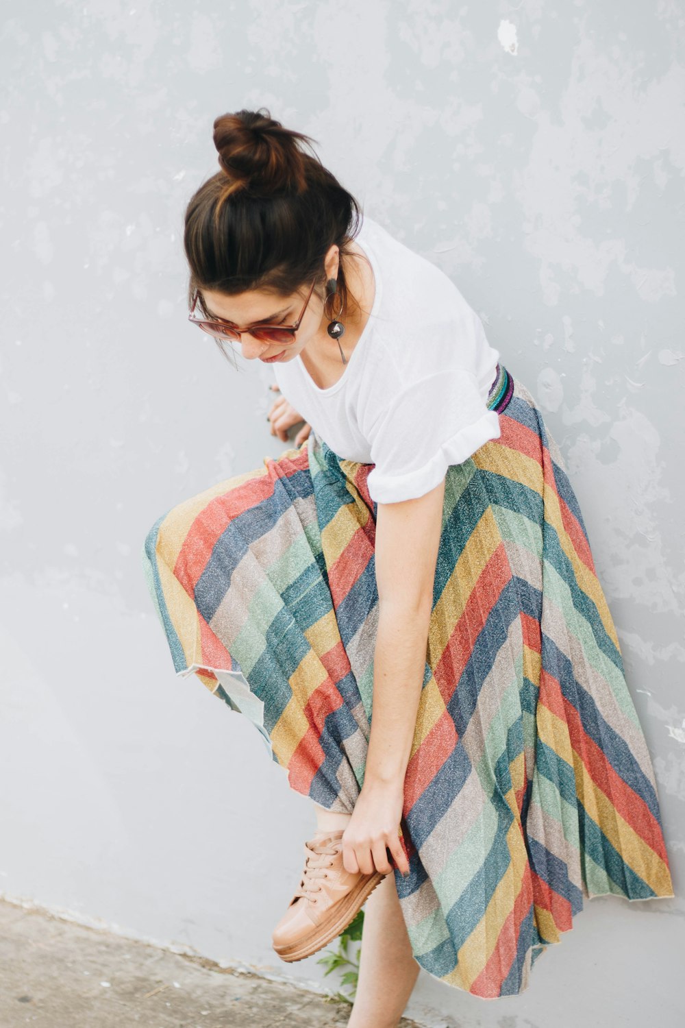 woman wearing white shirt and yellow, blue, and green striped long skirt