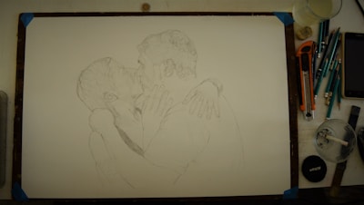 An artist sketching a romantic couple on paper with colored pencils and soft natural light.