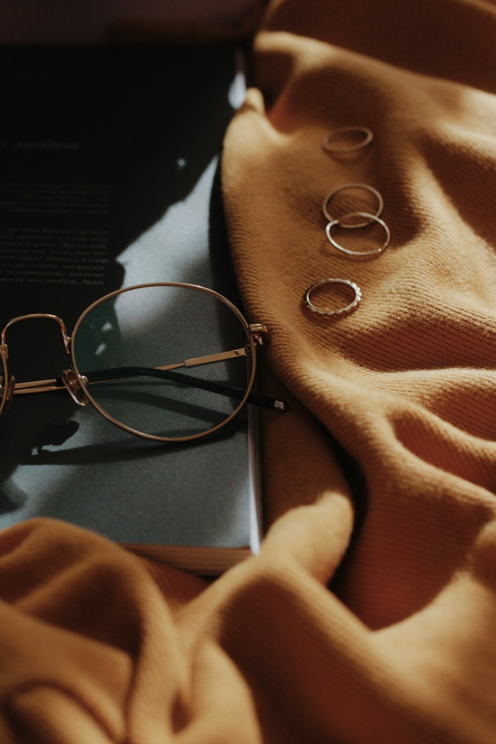 gray framed eyeglasses near four copper-colored accessories on orange sheet