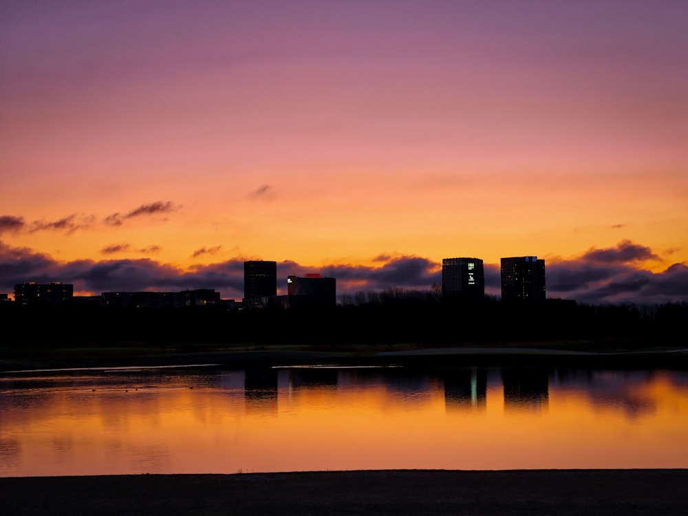 silhouette photo of building beside body of water during dawn