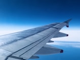 Close-up of a jet’s polished wingtip reflecting a clear blue sky.