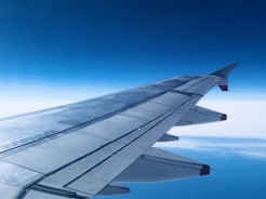 Close-up of fuel hoses connected to an airplane wing under a bright sky