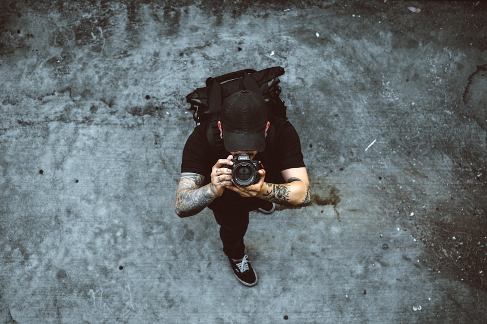 uomo che scatta foto mentre si trova su un terreno di cemento grigio