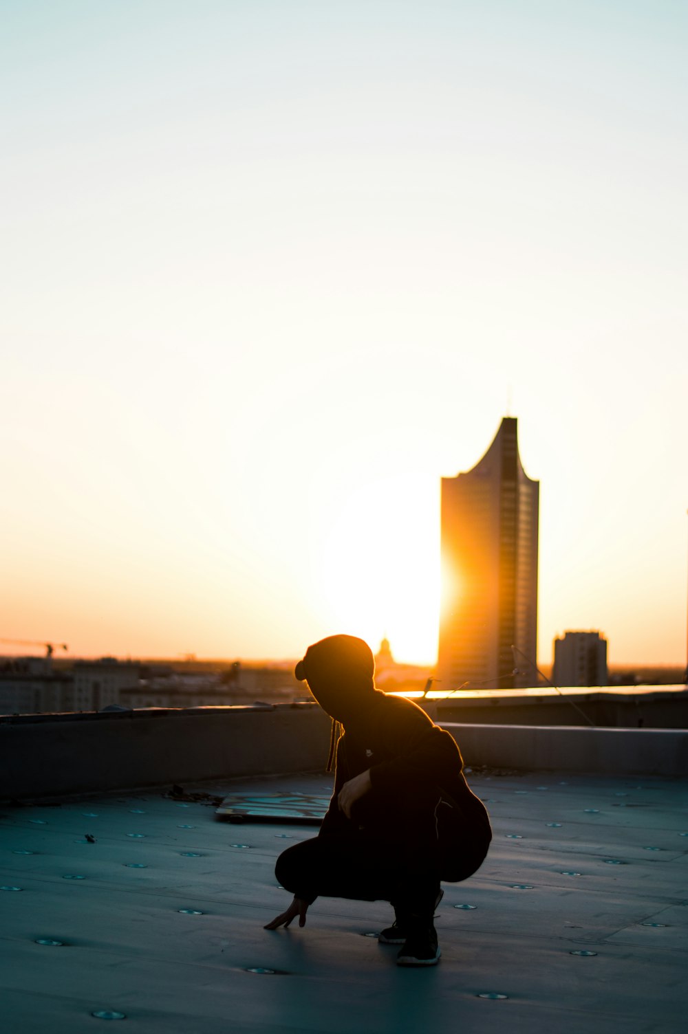 silhouette photography of woman squatting on rooftop