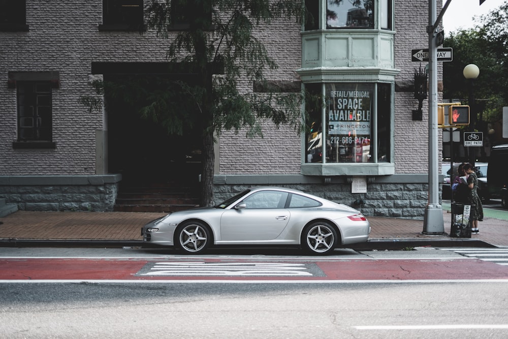 Un Porsche coupé plateado aparcado cerca de un edificio