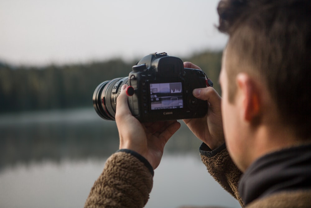 persona sosteniendo una cámara DSLR negra