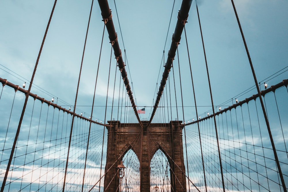 Photo en contre-plongée d’un pont suspendu en béton brun sous un ciel bleu de jour