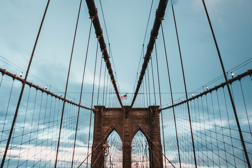 low angle photo of brown concrete suspension bridge under blue sky at daytime