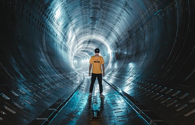low light photography of man standing inside tunnel