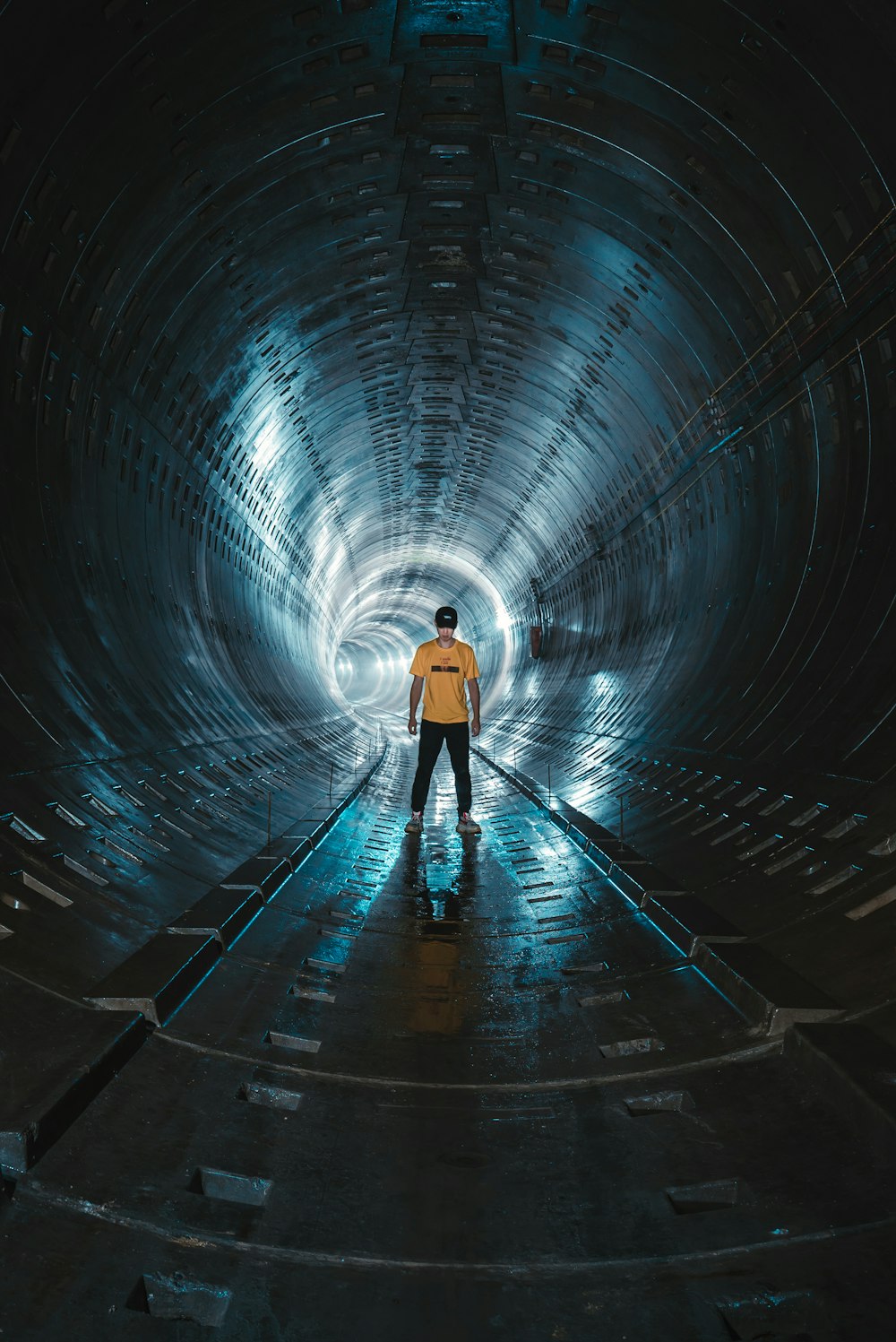 low light photography of man standing inside tunnel