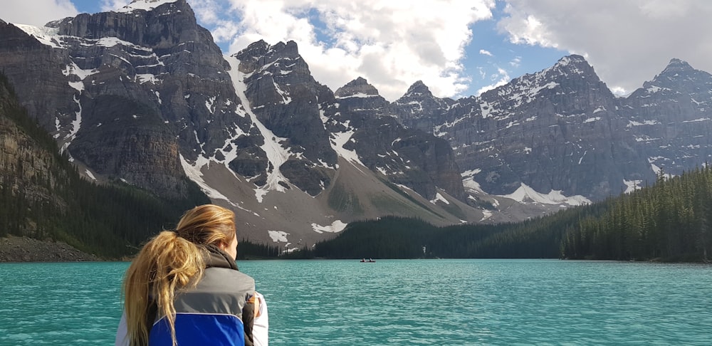 woman looking at body of water surrounded with trees during daytime