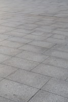 A surface covered with rectangular stone tiles arranged in a grid pattern. The tiles have a light gray color with slight variations in tone, giving a textured look.