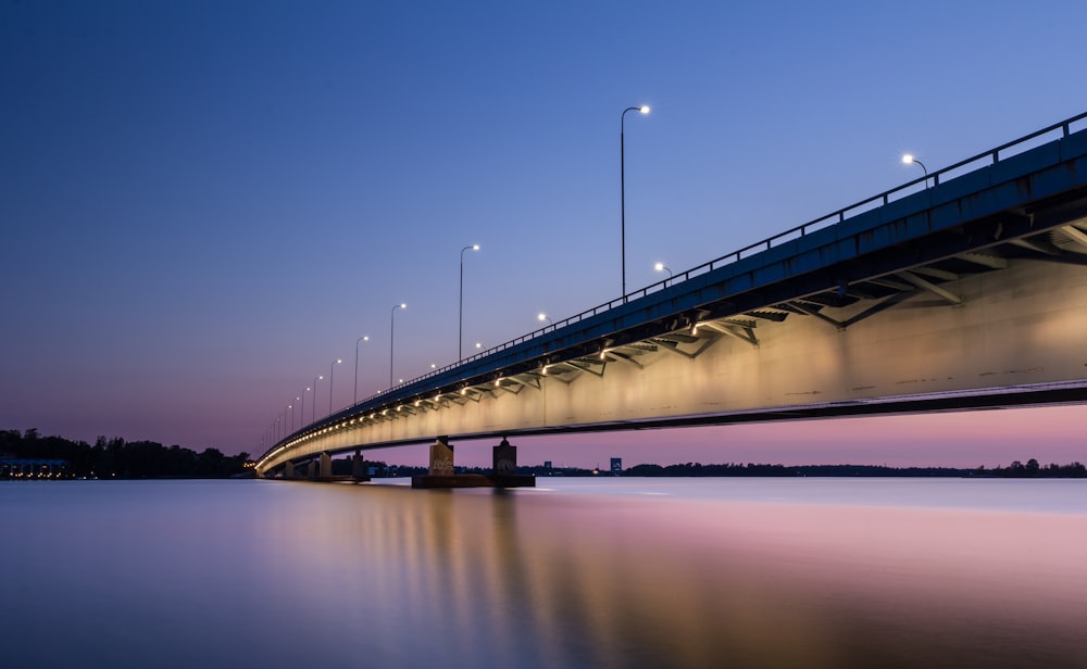 ponte in cemento grigio con specchio d'acqua durante la notte