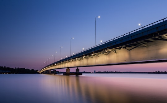 gray concrete bridge with body of water during nighttime in Helsinki Finland