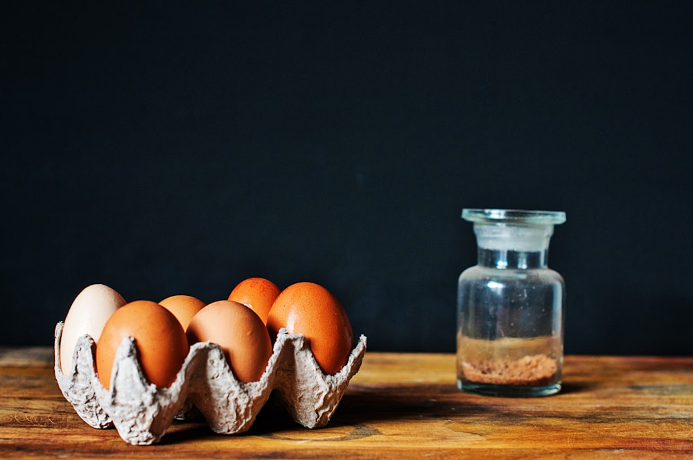 brown eggs in tray near clear glass bottle