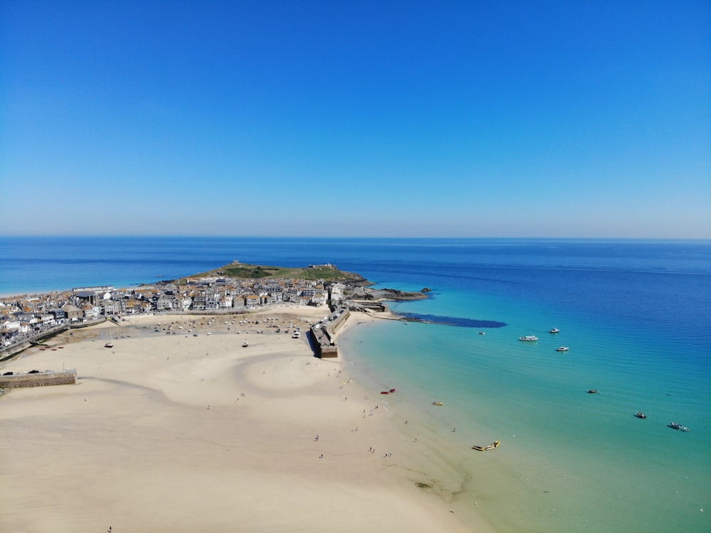 aerial photo of ruin buildings beside large blue body of water under blue sky at daytime