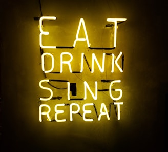 turned on eat drink sing repeat neon signage on wall