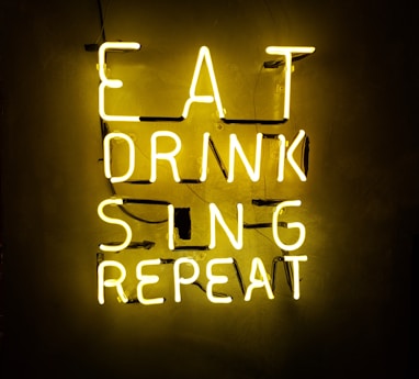 turned on eat drink sing repeat neon signage on wall