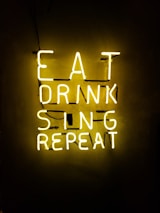 turned on eat drink sing repeat neon signage on wall