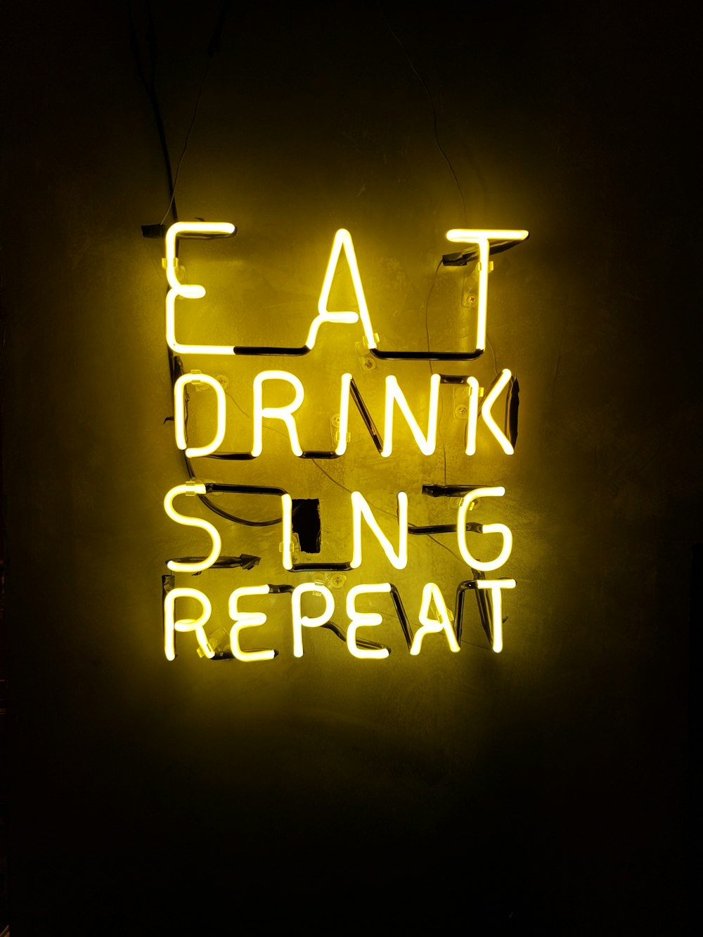 turned on eat drink sing repeat neon signage on wall