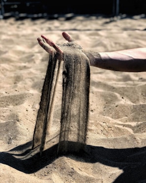A close-up of hands creating a sandplay scene in a sandbox.