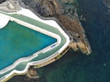 Aerial view of a premium swimming pool integrated with natural rocks and a wooden deck