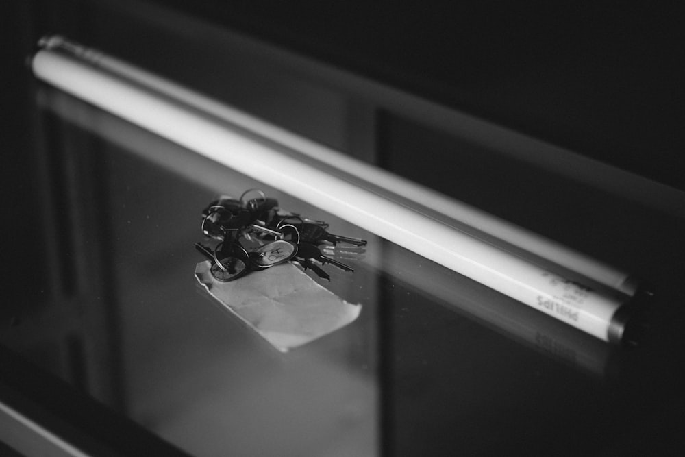 grayscale photography of fluorescent light tube placed beside keys