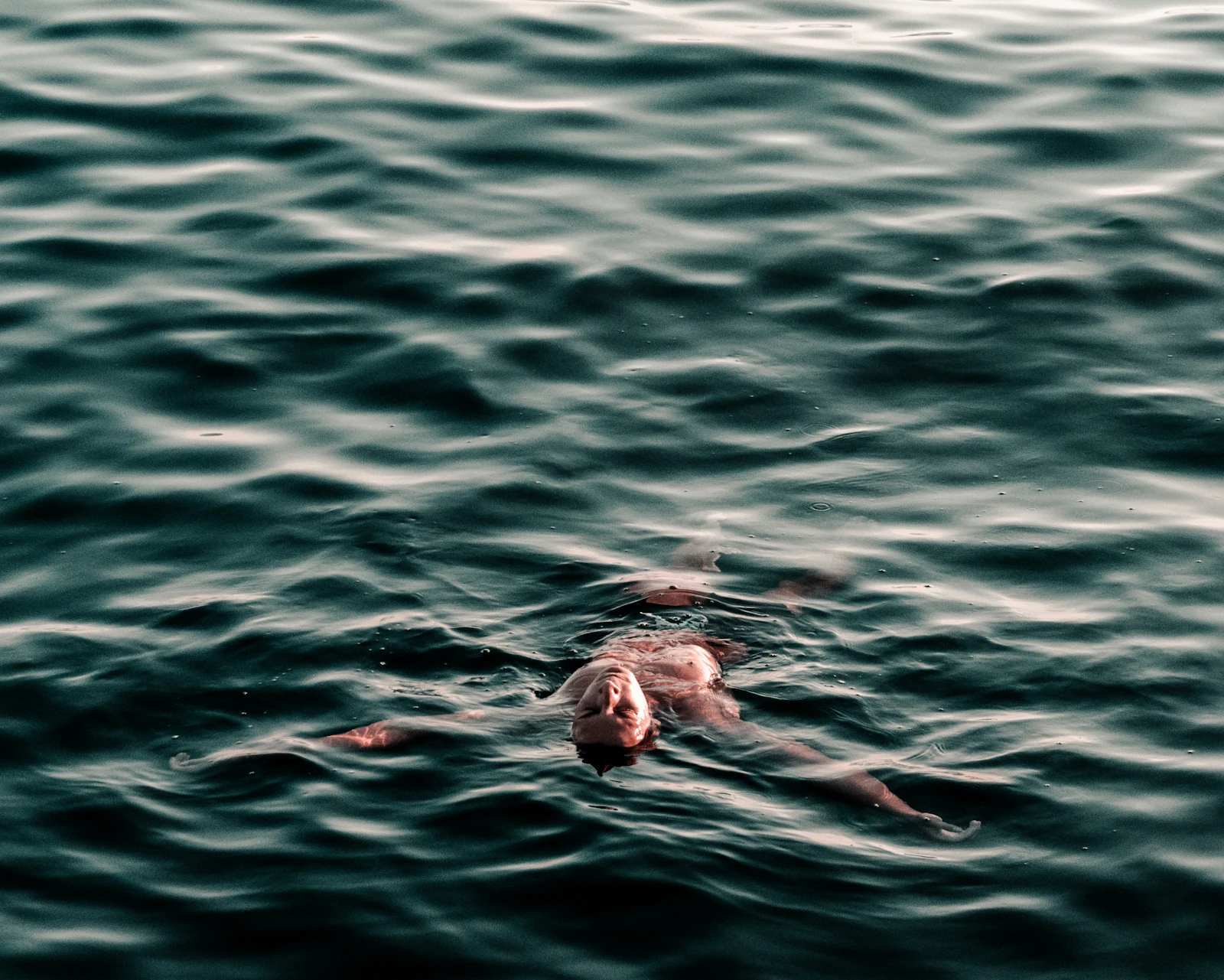 Diver descending into deep blue cold water