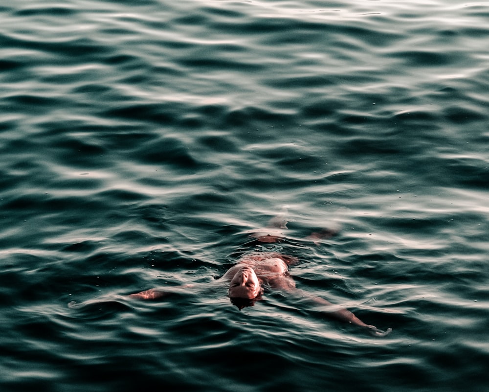 hombre nadando hacia atrás en el cuerpo de agua