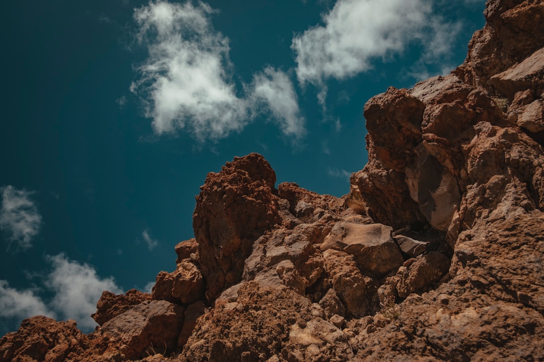 low-angle photography of rock formation under cloudy sky