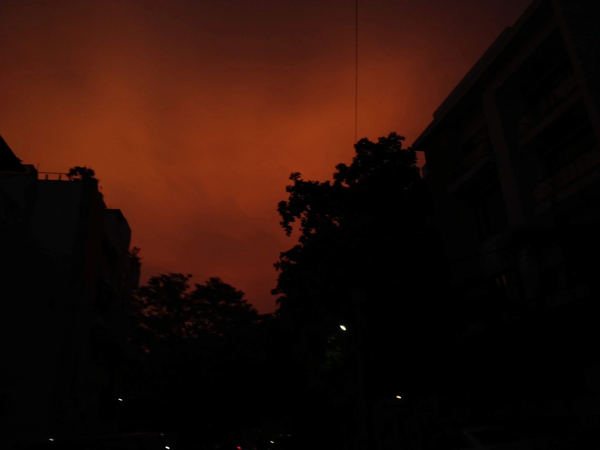 A cinematic still capturing a moody urban night scene with deep shadows and vibrant yellow-orange highlights.