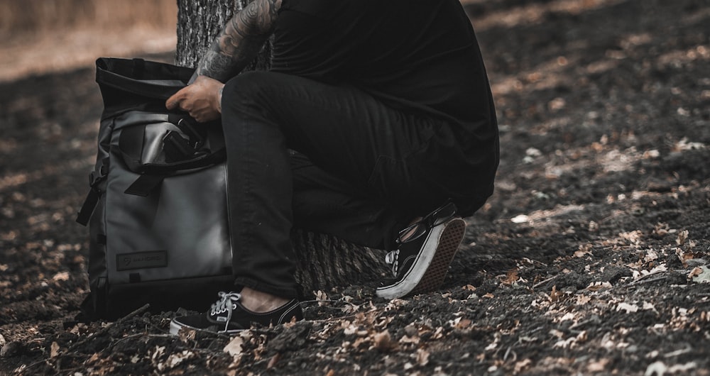 person holding gray and black backpack