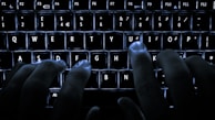 Hands typing on a keyboard with a dark-themed interface and red highlights.