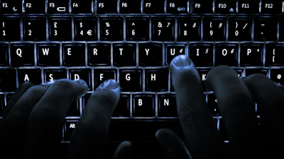 Close-up of hands typing on a keyboard with a dark, clean background.
