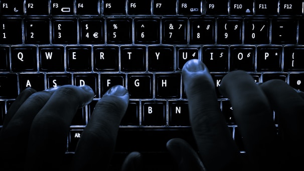 Hands typing on a keyboard with a blurred background of a minimalist office.