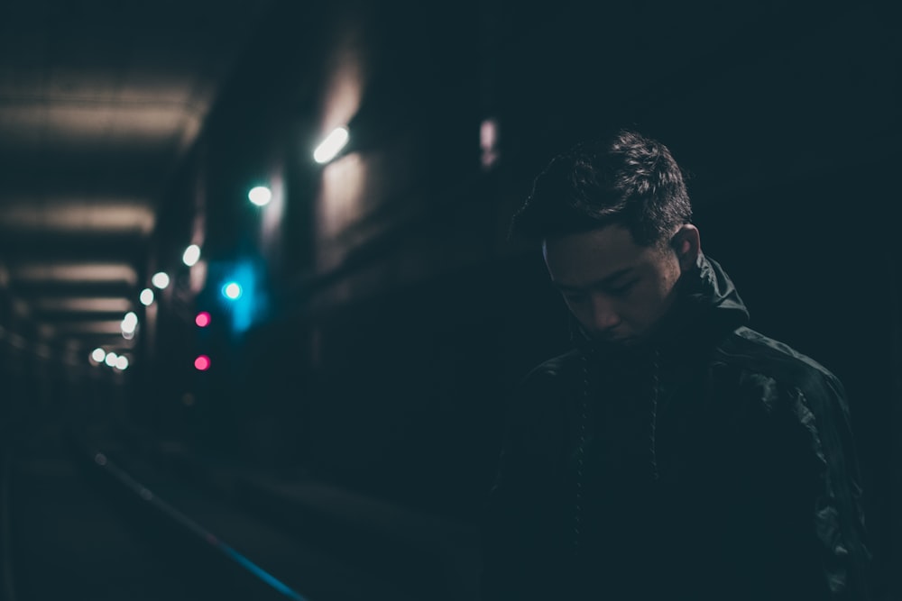 close-up photo of man in black jacket standing inside tunnel