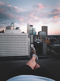 A person stretching on a sunny morning rooftop with a city view.