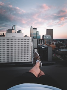 A person stretching on a sunny morning rooftop with a city view.