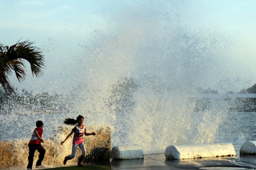 Children playing near the coastline of Acapulco with a backdrop of the city.
