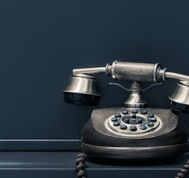 black and brown rotary phone near gray wall