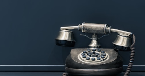 black and brown rotary phone near gray wall