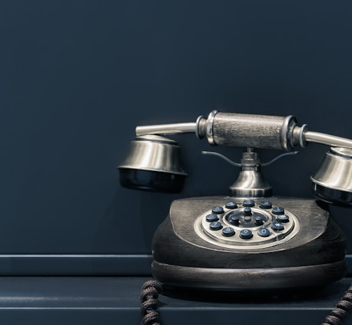 black and brown rotary phone near gray wall