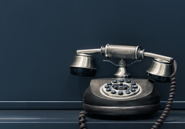 black and brown rotary phone near gray wall