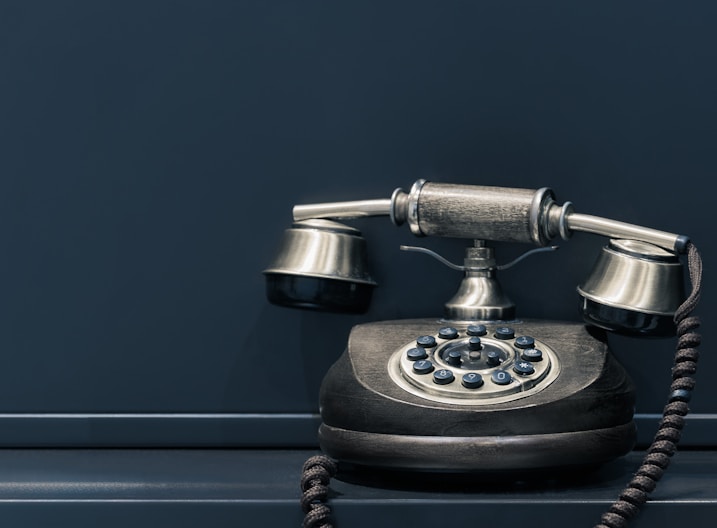 black and brown rotary phone near gray wall