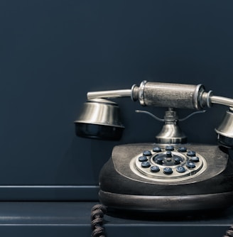 black and brown rotary phone near gray wall