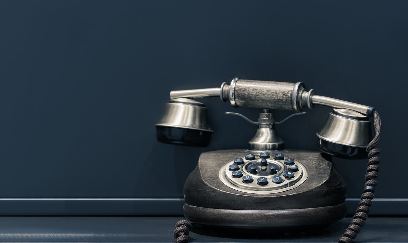 black and brown rotary phone near gray wall